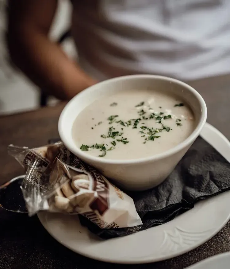 A bowl of creamy Boston clam chowder served with crackers
